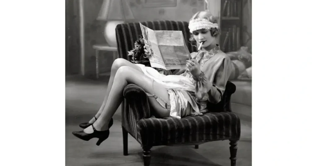 Exploring Vintage Fashion - Woman with heels sitting on the armchair and reading a newspaper