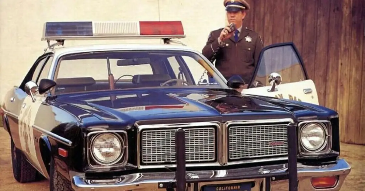 Vintage Police Car -Cop standing nex tto his car speaking in his radio device