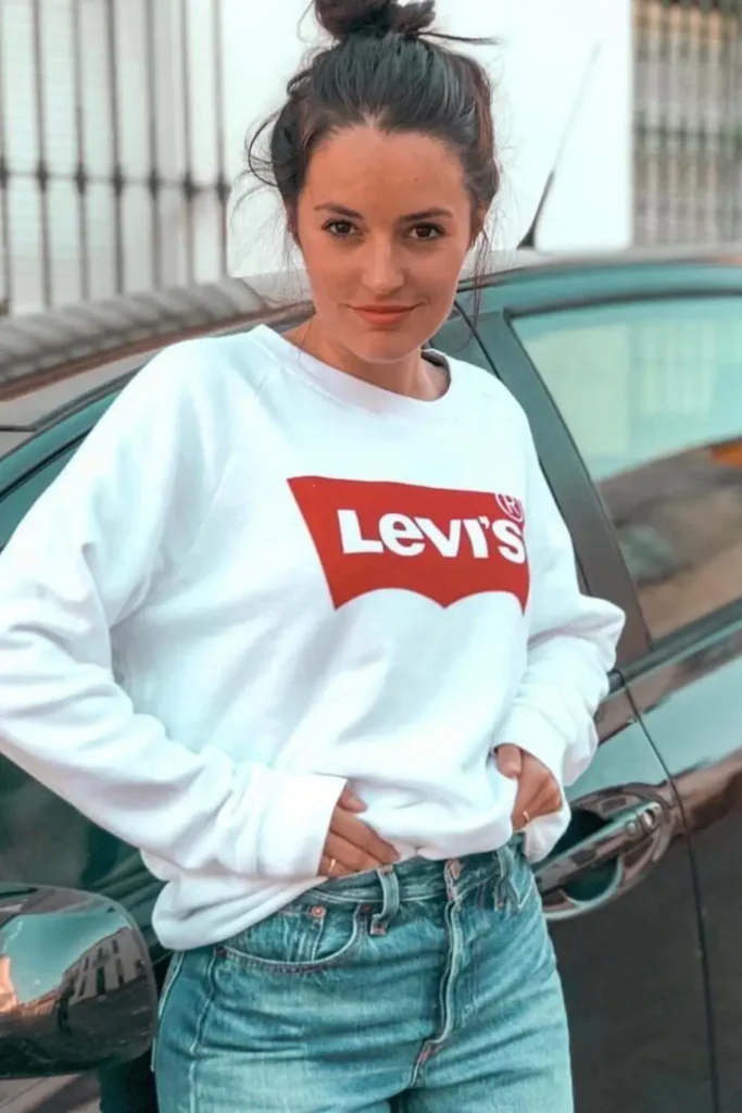 Woman next to a car with a Levi's Vintage Sweatshirt in white with red logo